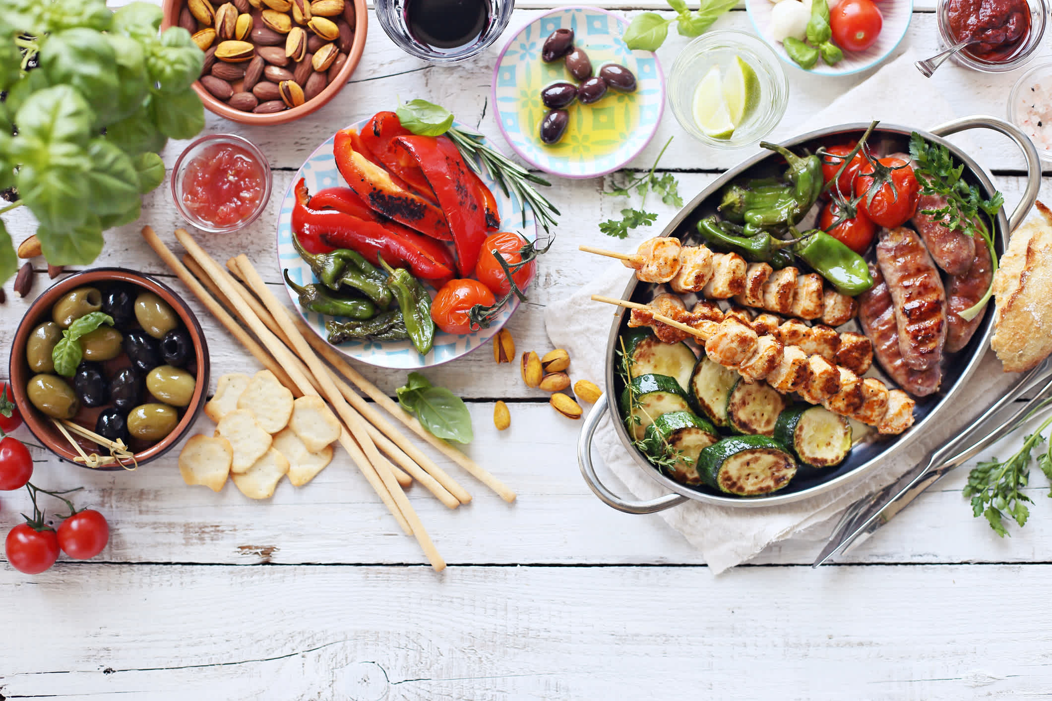 A table with traditional Greek food - grilled meat, vegetables and olives. 