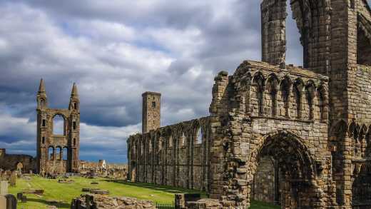 Blick auf die Ruine der St Andrews Cathedral mit noch stehenden Steinwänden und Türmen auf einer grünen Wiese