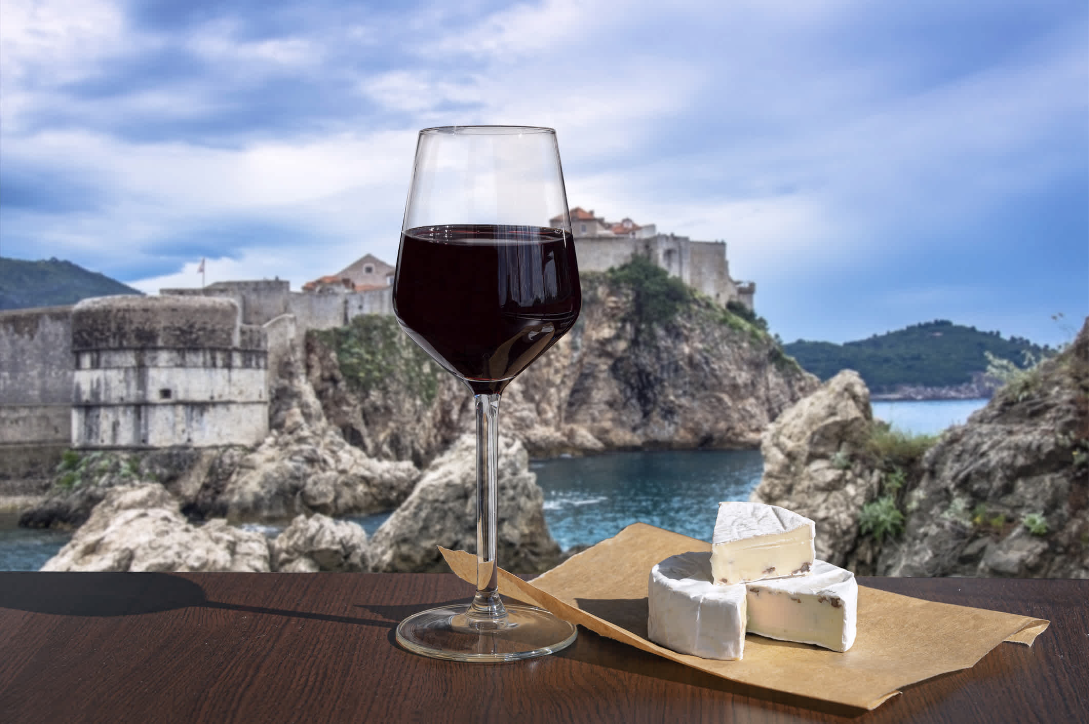Ein Glas Rotwein mit Brie-Käse mit Blick auf die Altstadt von Dubrovnik.
