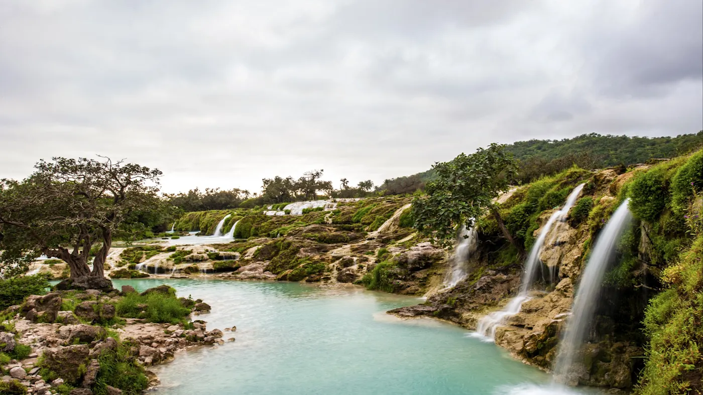 Wasserfälle und türkisfarbene Pools in einer üppigen grünen Landschaft. Salalah, Dhofar, Oman.