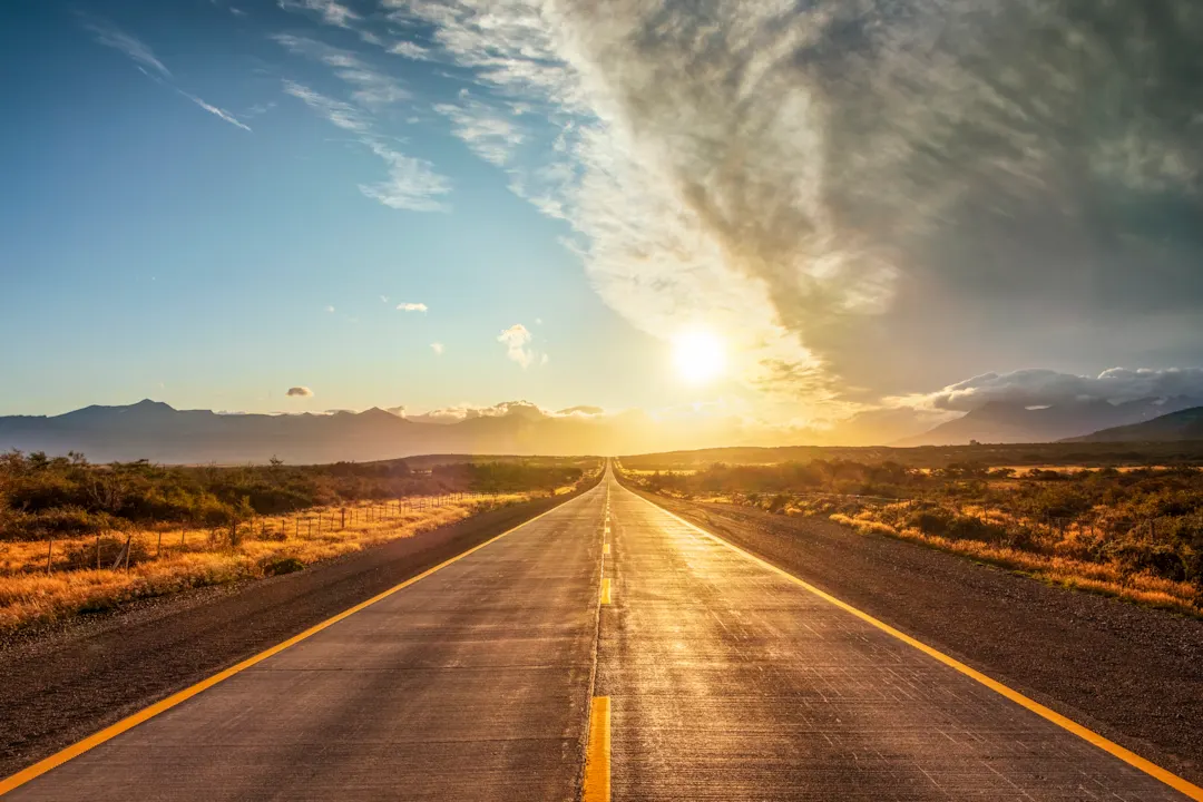 Straße in Patagonien mit aufgehender Sonne im Hintergrund