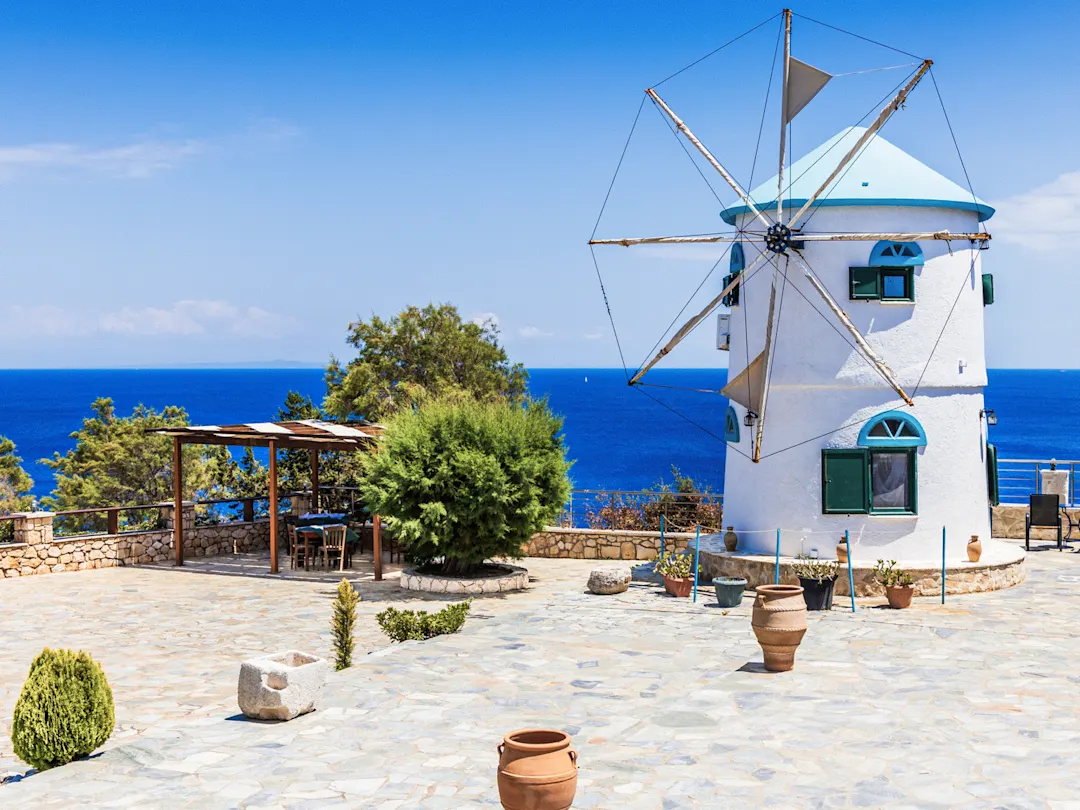 Traditionelles Windmühlen mit Blick auf das blaue Meer unter einem klaren Himmel, Zakynthos, Griechenland.