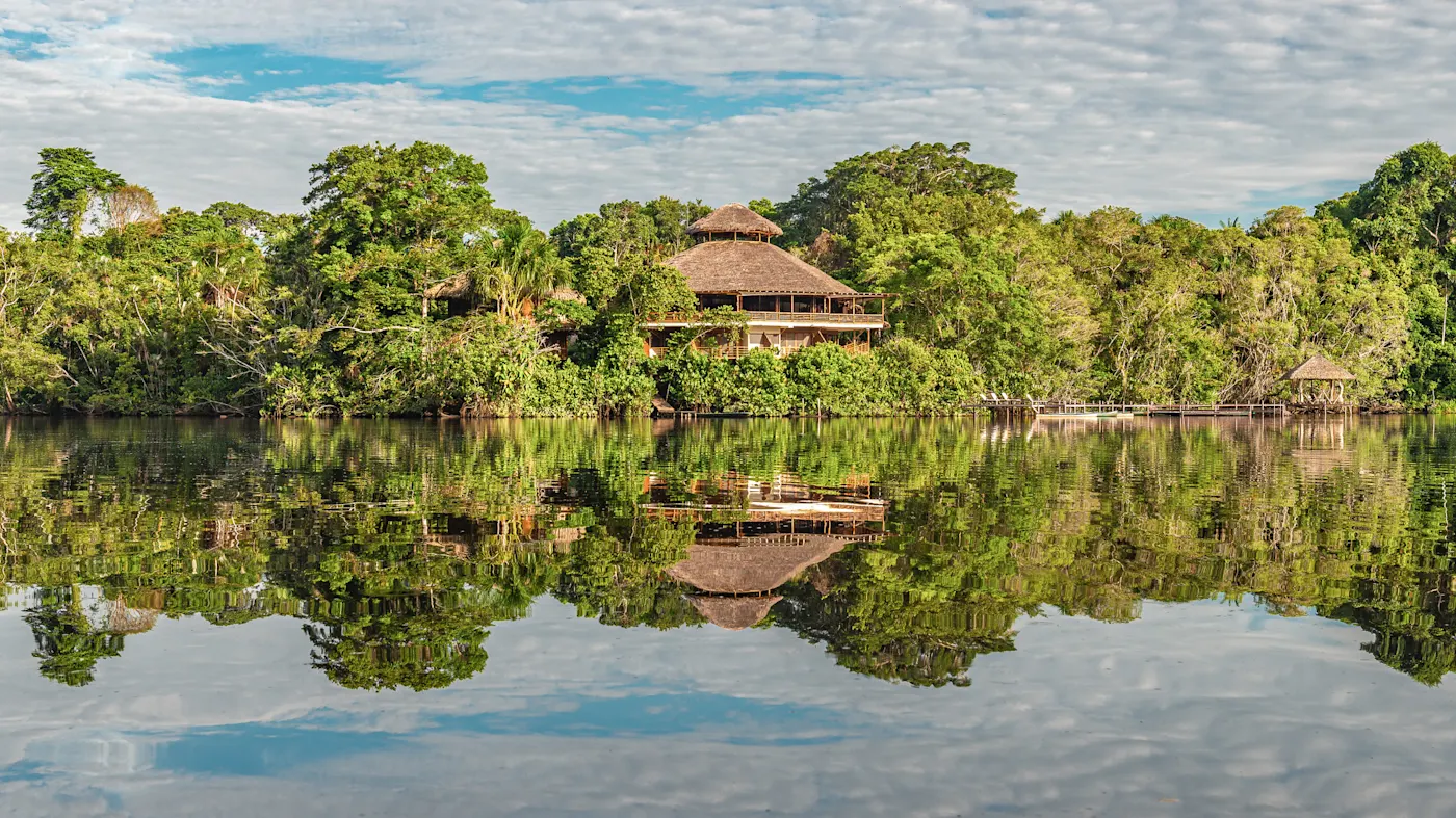 Brasilien, Amazonas, Öko-Lodge Eine Öko-Lodge mit Strohdach spiegelt sich im ruhigen Fluss des Amazonas-Regenwaldes. Amazonas, Brasilien.