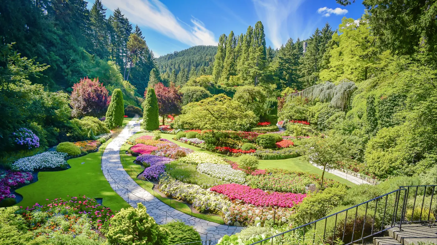 Victoria, Vancouver Island, British Columbia, Kanada Farbenfroher Garten mit Blumenbeeten und einem kurvigen Weg, umgeben von Bäumen. Victoria, Vancouver Island, British Columbia, Kanada.
