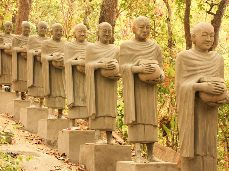 Battambang, Kambodscha Reihe von buddhistischen Mönchsstatuen mit Almosenschalen in einem Wald, Provinz Battambang, Kambodscha.