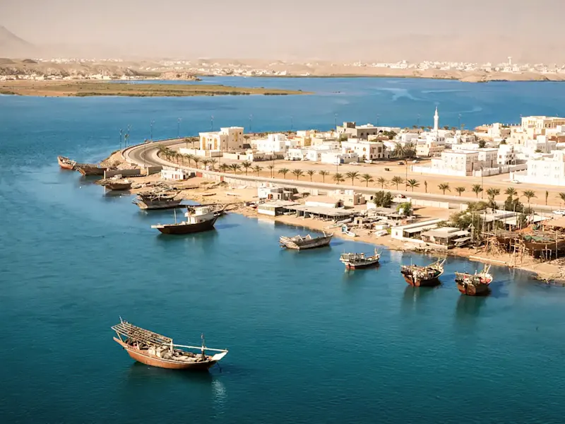 Traditionelle Dhau-Boote im Hafen mit weißen Gebäuden. Sur, Ash Sharqiyah, Oman.
