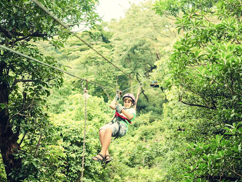 Costa Rica, Seilrutsche Junge auf einer Seilrutsche durch den tropischen Regenwald mit üppiger Vegetation. Costa Rica.