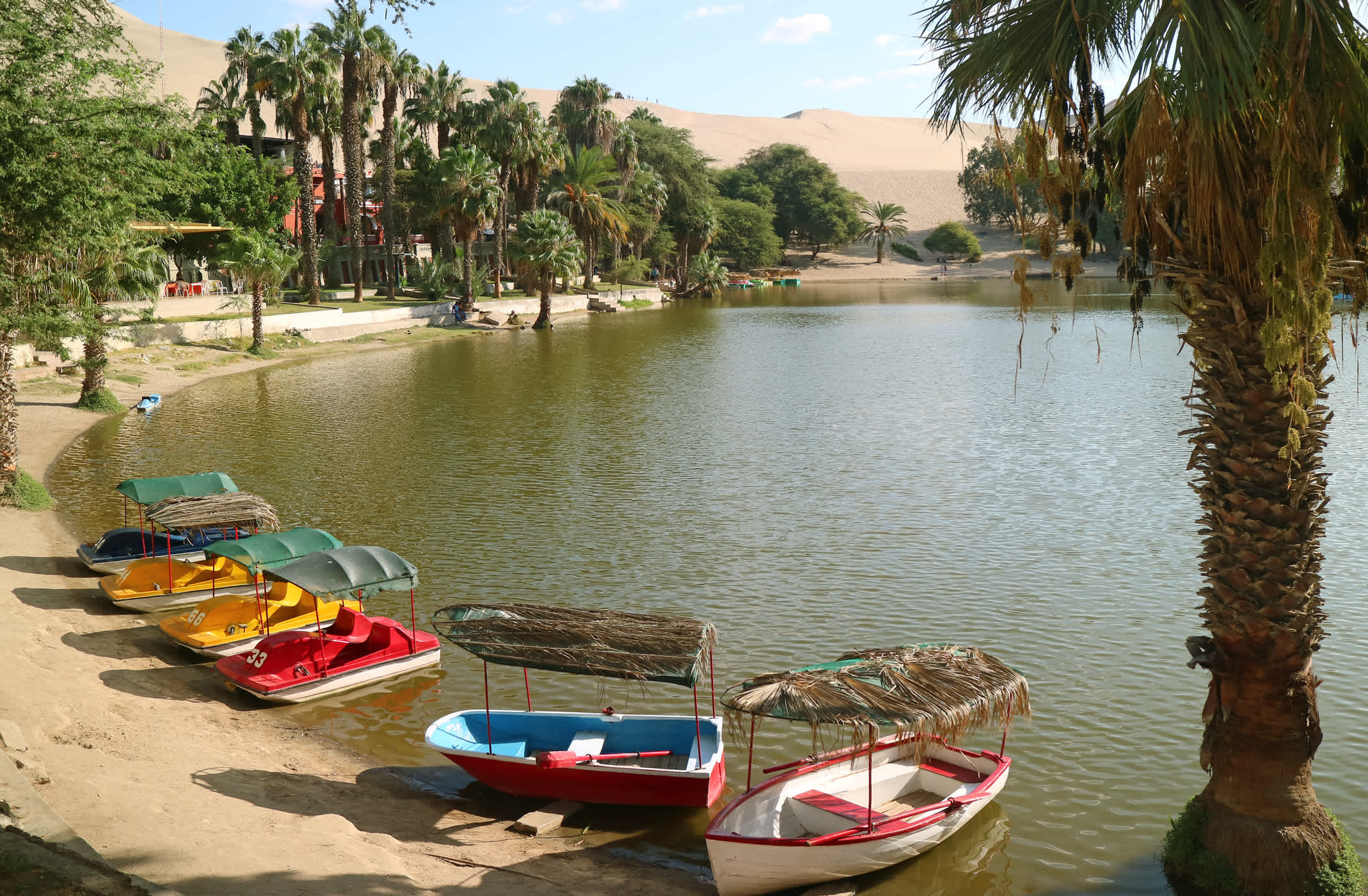 Bunte Boote am Ufer der Oasenlagune im Dorf Huacachina in Ica (Peru), Südamerika 