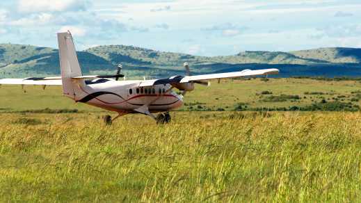 Un petit avion de ligne à hélices qui vient d'atterrir sur une prairie verte au Kenya.