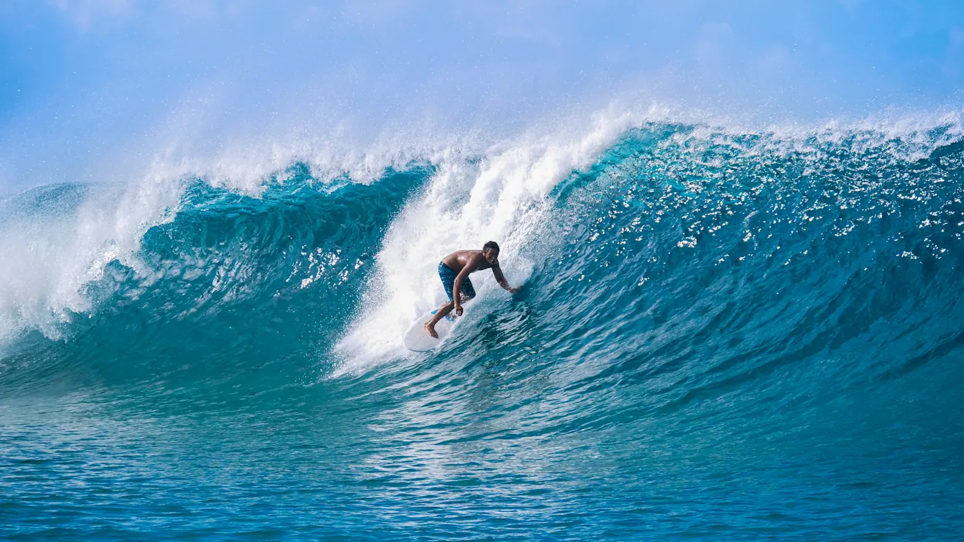 Surfer reitet eine große, türkisfarbene Welle mit kraftvollem Schwung. Französisch-Polynesien.