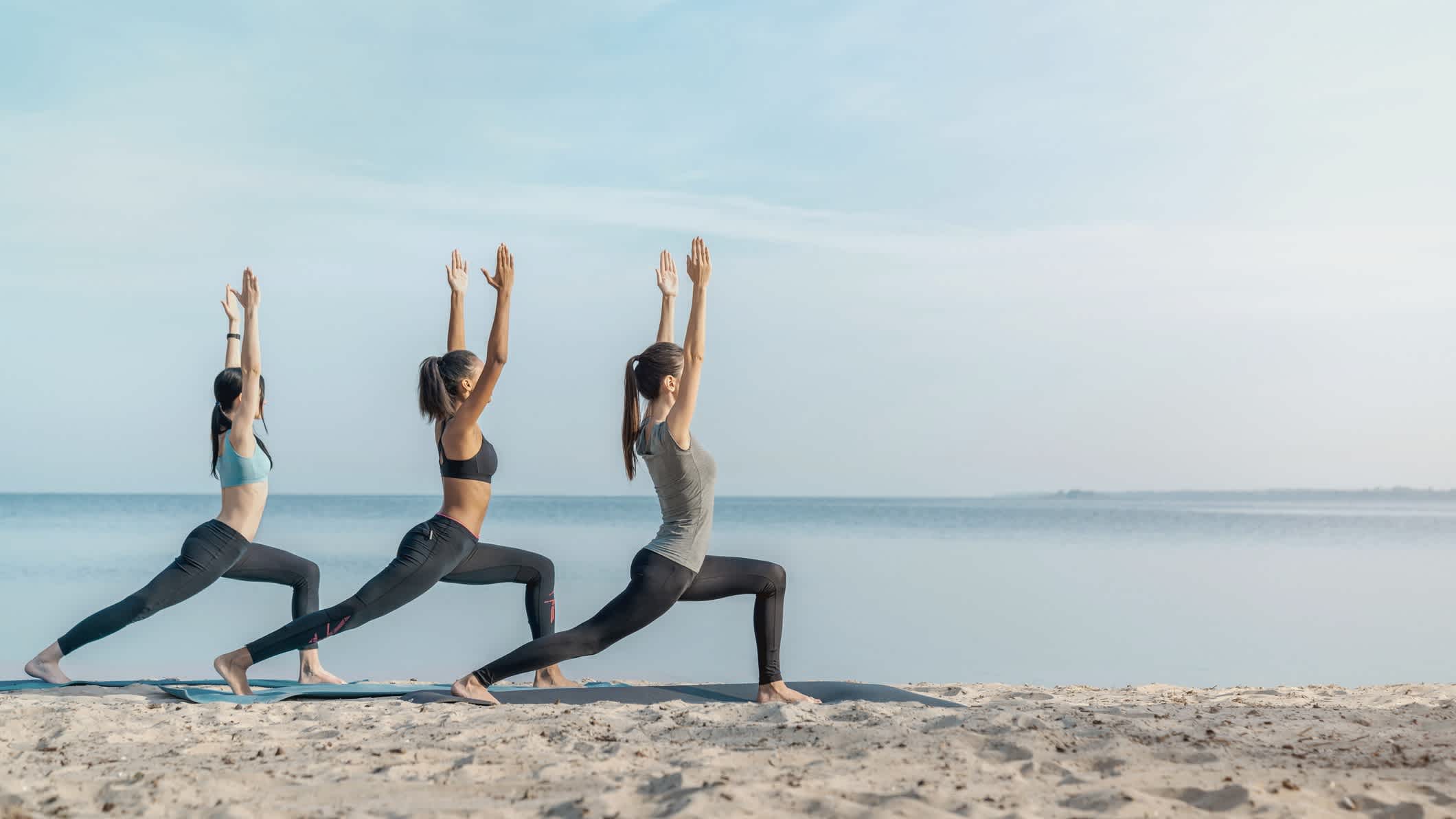 Gruppe von Frauen übt Yoga am Strand