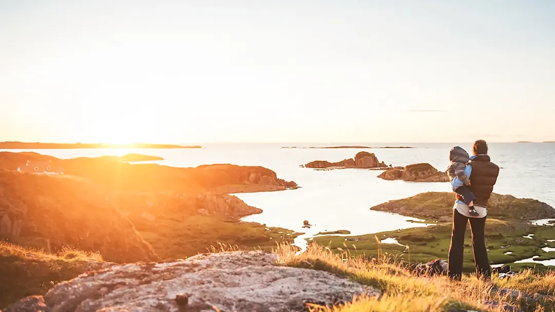 Mutter und Sohn in den schottischen Highlands bein Familienurlaub blicken auf das Meer bei Sonnenuntergang