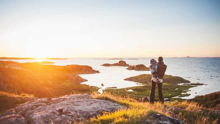 Mutter und Sohn in den schottischen Highlands bein Familienurlaub blicken auf das Meer bei Sonnenuntergang