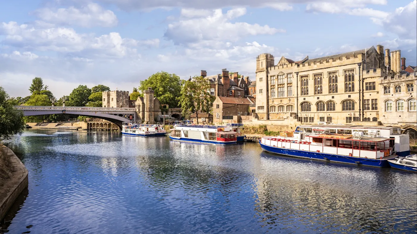 York, England, Vereinigtes Königreich Flusslandschaft mit historischen Gebäuden und Booten unter blauem Himmel. York, England, Vereinigtes Königreich.