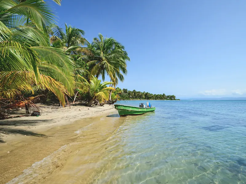 Boot und Palmen am tropischen Strand mit klarem Wasser. Bocas del Toro, Bocas del Toro, Panama.