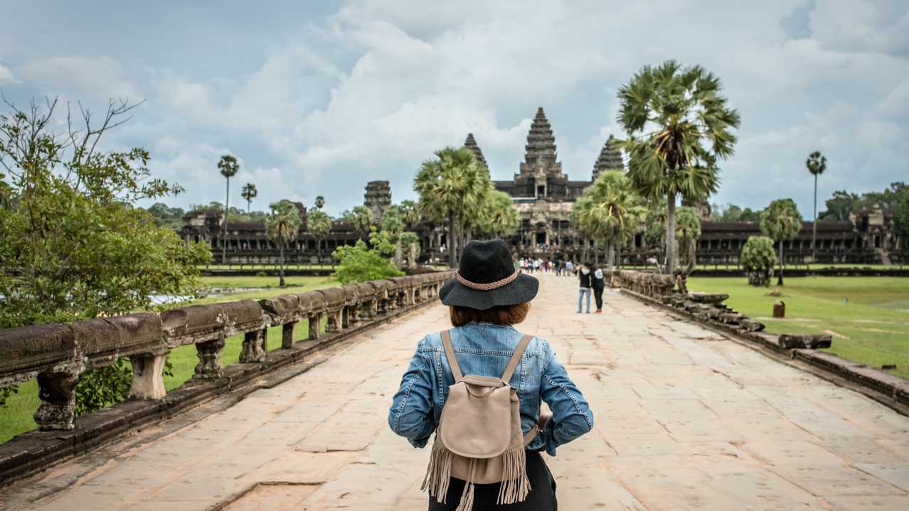 Femme de dos avec un chapeau et un sac à dos regardant Angkor Wat, au Cambodge