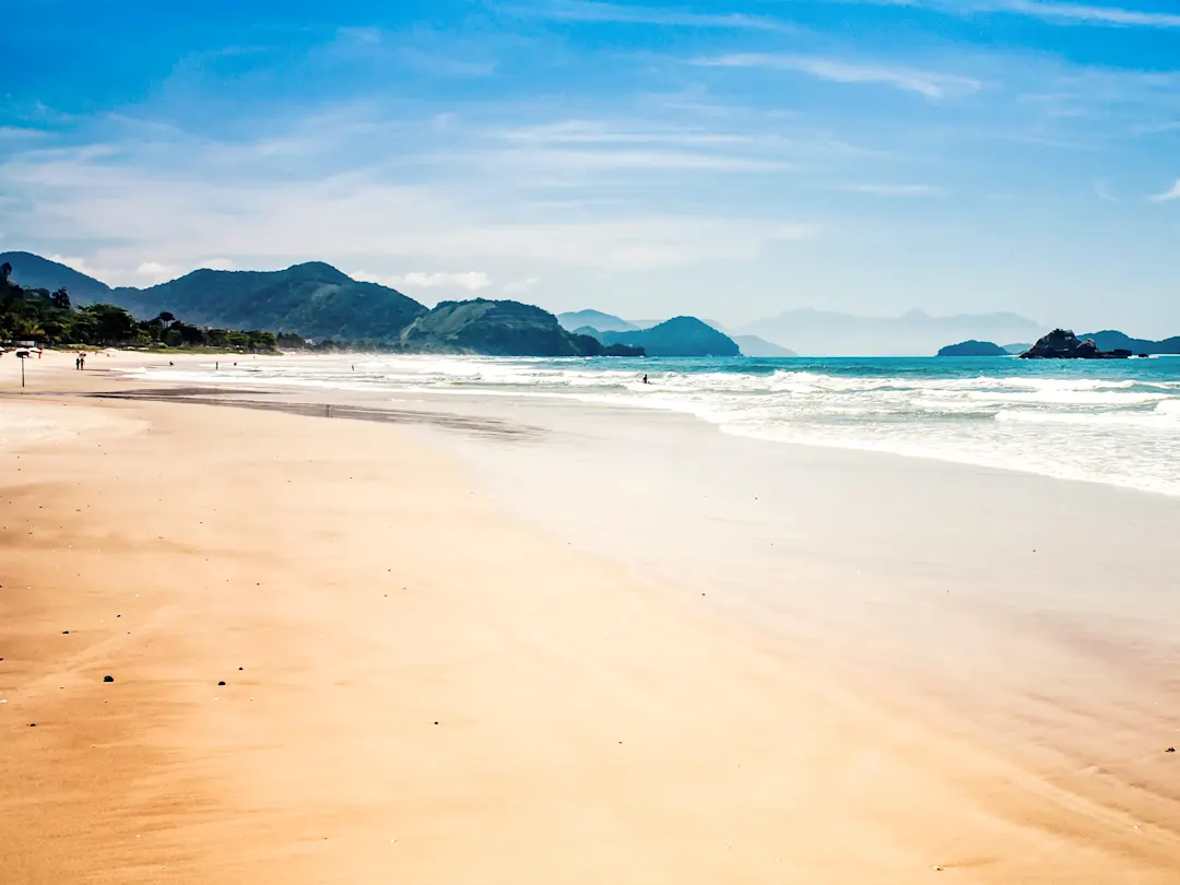 Weitläufiger Sandstrand mit Wellen und Bergen. Ilha Grande, Rio de Janeiro, Brasilien.
