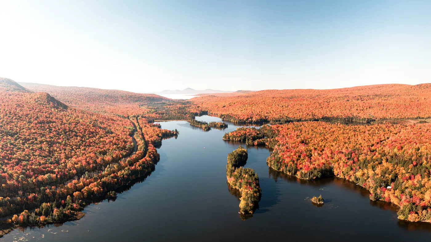 Neuengland, USA Herbstliche Luftbildaufnahme eines Sees mit zahlreichen Inseln, umgeben von leuchtend roten Wäldern. Neuengland, USA