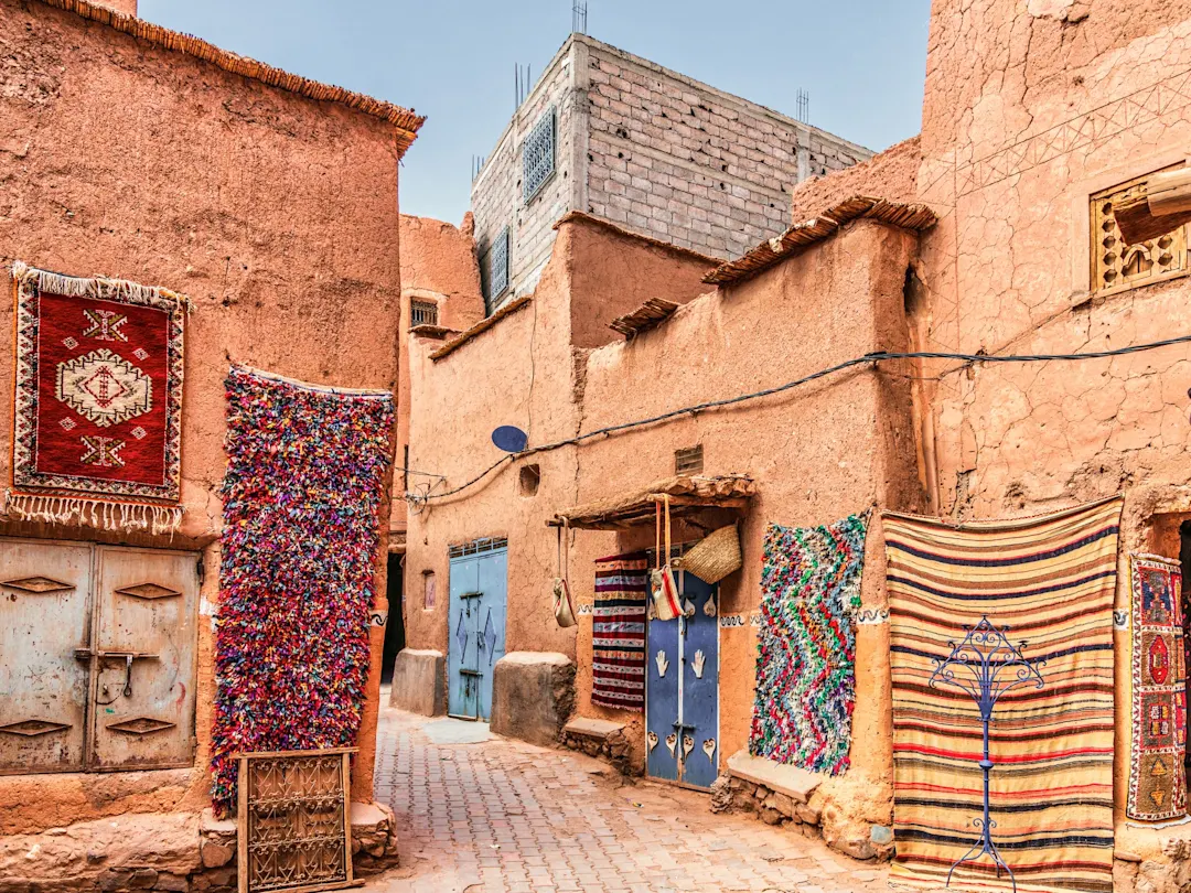 Traditionelle Berber-Teppiche an Lehmbauten in einer Gasse. Marrakesch, Marrakesch-Safi, Marokko.