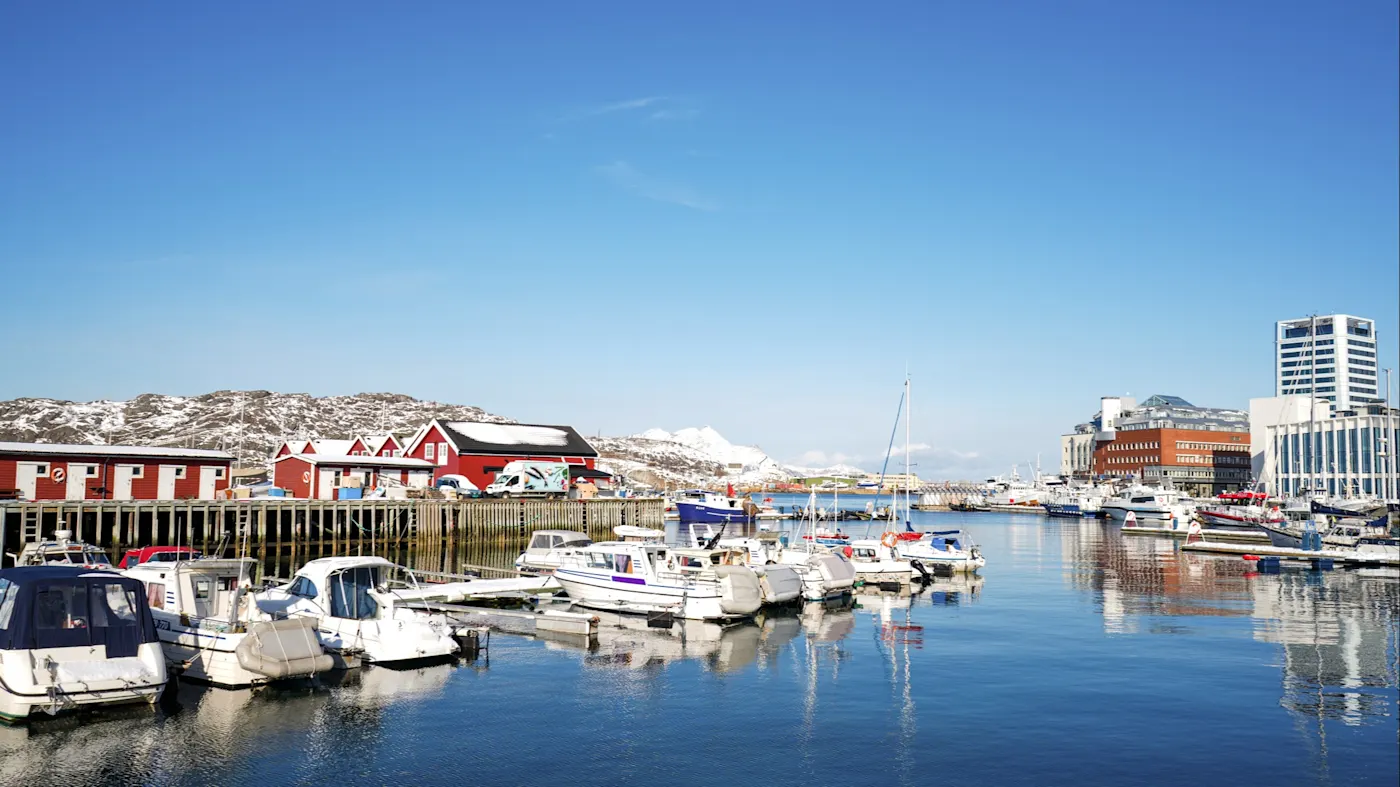 Bodø, Nordland, Norwegen Hafen von Bodø mit Booten und roten Häusern vor dem klaren blauen Himmel. Bodø, Nordland, Norwegen.