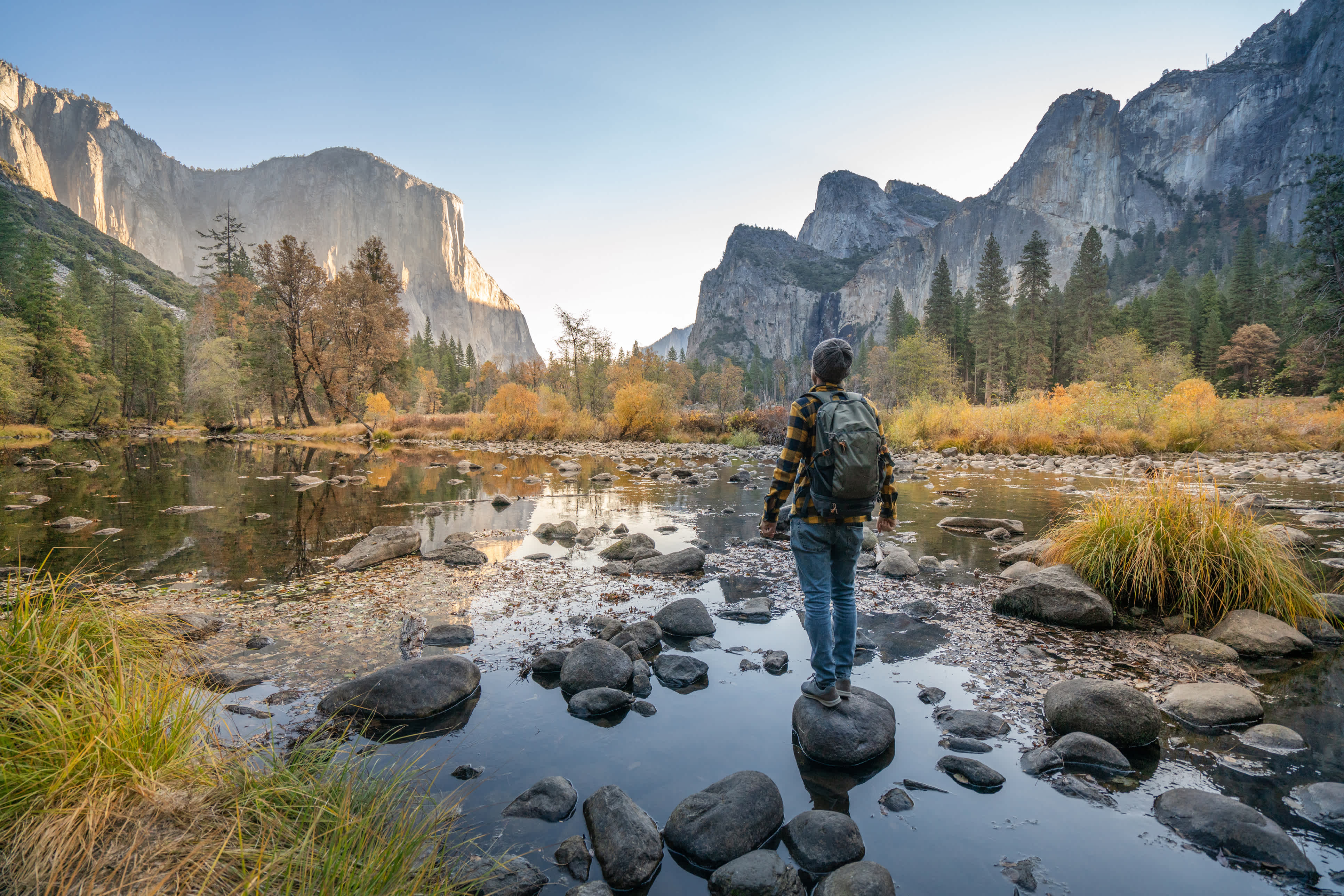 Junger Mann betrachtet Yosemite-Tal vom Fluss aus, Reflexionen auf der Wasseroberfläche