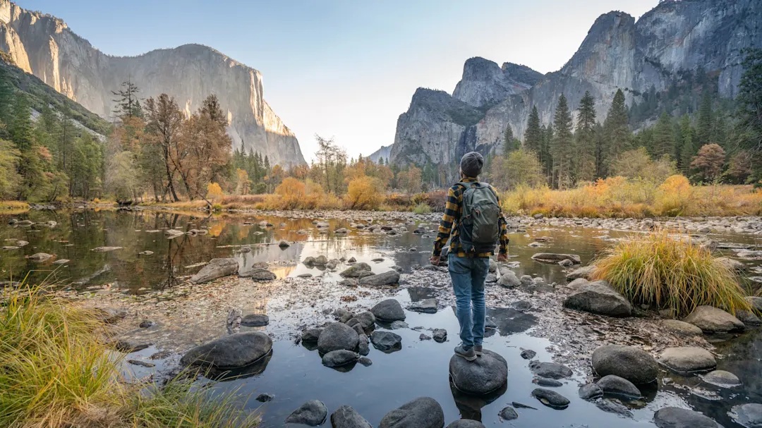 Junger Mann betrachtet Yosemite-Tal vom Fluss aus, Reflexionen auf der Wasseroberfläche