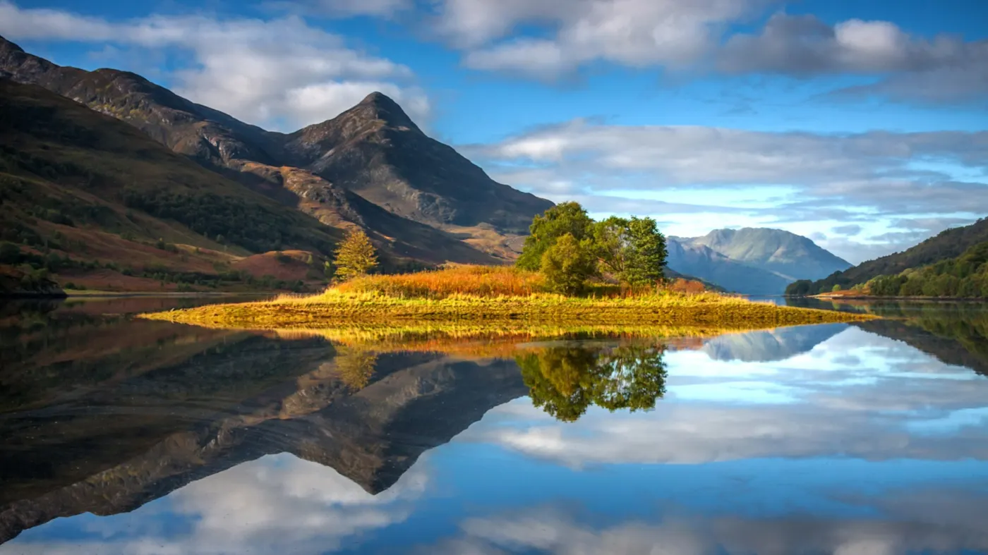 Blick auf eine kleine Insel im Loch Leven bei Glencoe umgeben von einer prächtigen Hügellandschaft