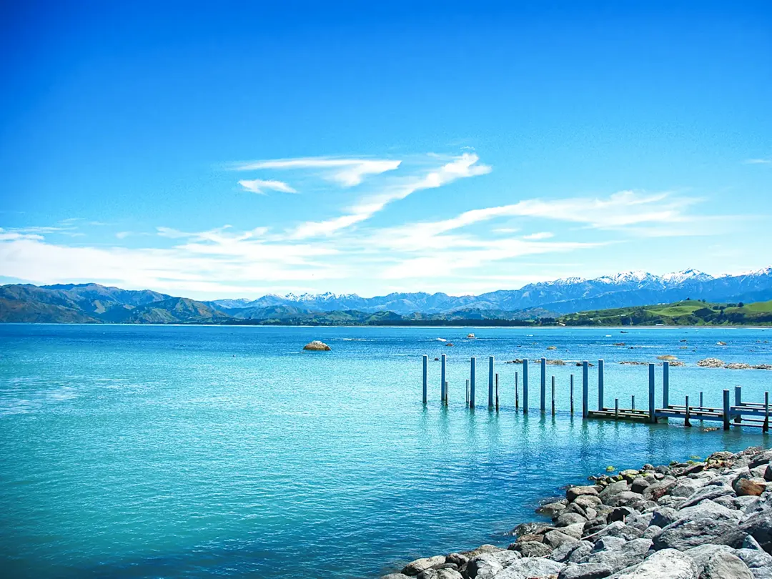 Blauer Ozean mit Bergblick und Steg. Kaikoura, Canterbury, Neuseeland.
