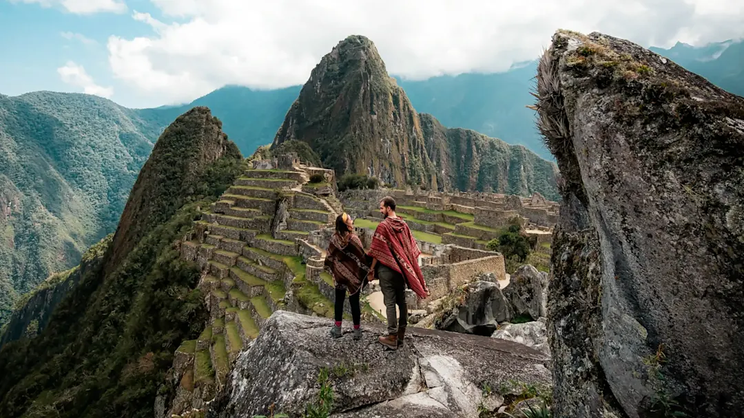 Paar mit Poncho schaut auf die Machu Picchu Ruinen während einer Flitterwochenreise. Peru.