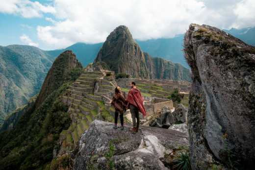 Paar mit Poncho schaut auf die Machu Picchu Ruinen während einer Flitterwochenreise