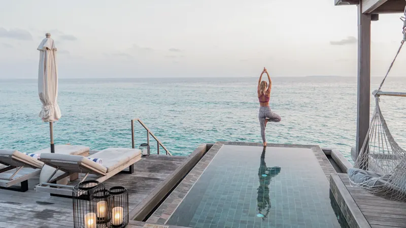 Maledives, Yoga, femme Séance de yoga sur une terrasse privée avec vue sur l'océan. Maldives.