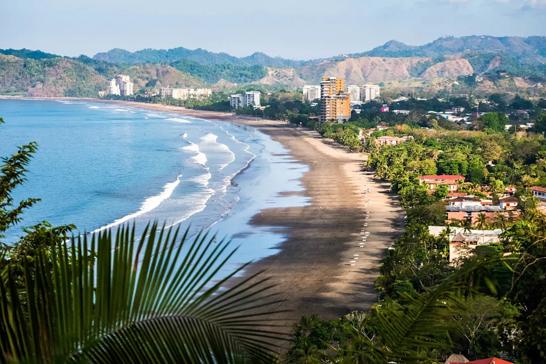 Kontrast zwischen dem Strand und den Gebäuden der Stadt, Jacó, Costa Rica