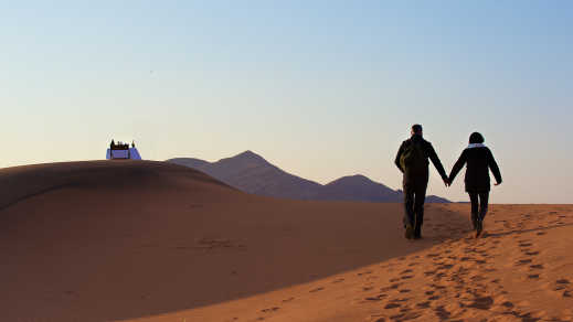 Couple sur une de dune de sable rouge se tenant par la main lors d'un voyage de noces en Namibie