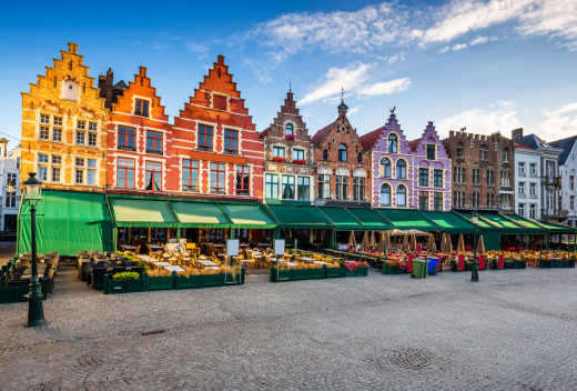 The market in the Grand Place of Antwerp at sunrise, framed by colourful houses typical of Belgian architecture. A city to discover during your holidays in Belgium.