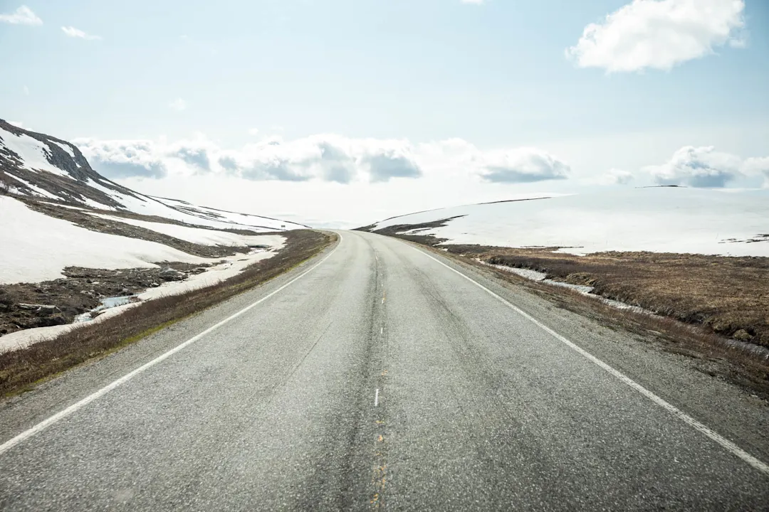Straße, unberührte Natur, Schnee, bewölkt, blauer Himmel 