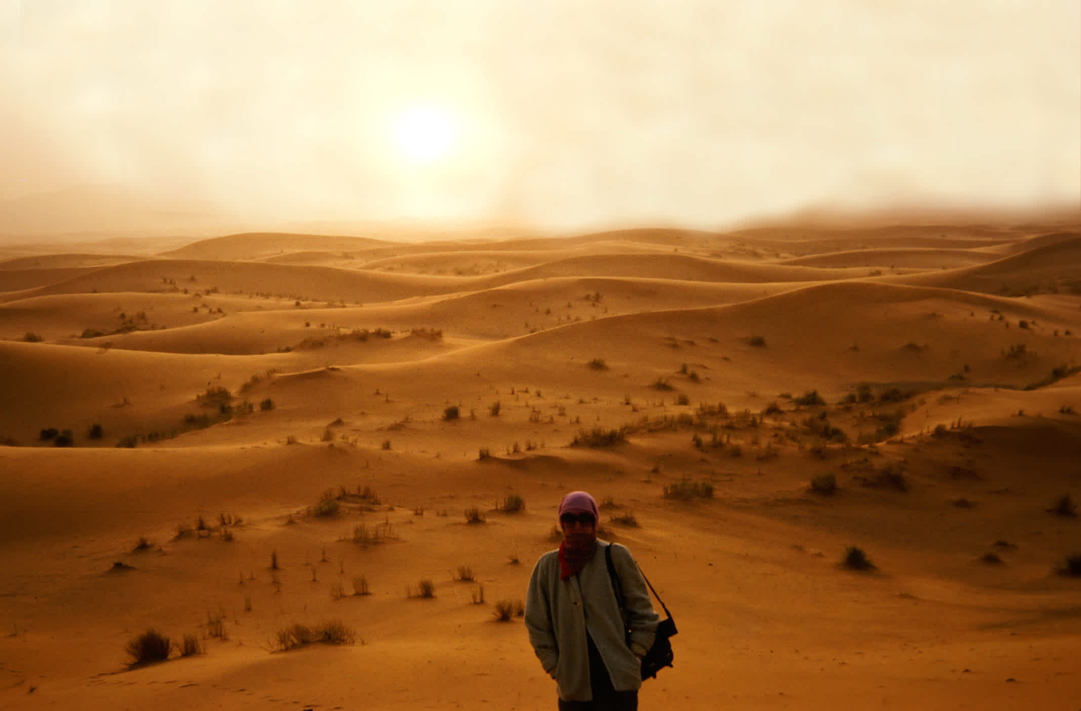 Eine Frau auf einer Sanddüne in der Nähe von Rissani in der marokkanischen Wüste bei Sonnenuntergang.