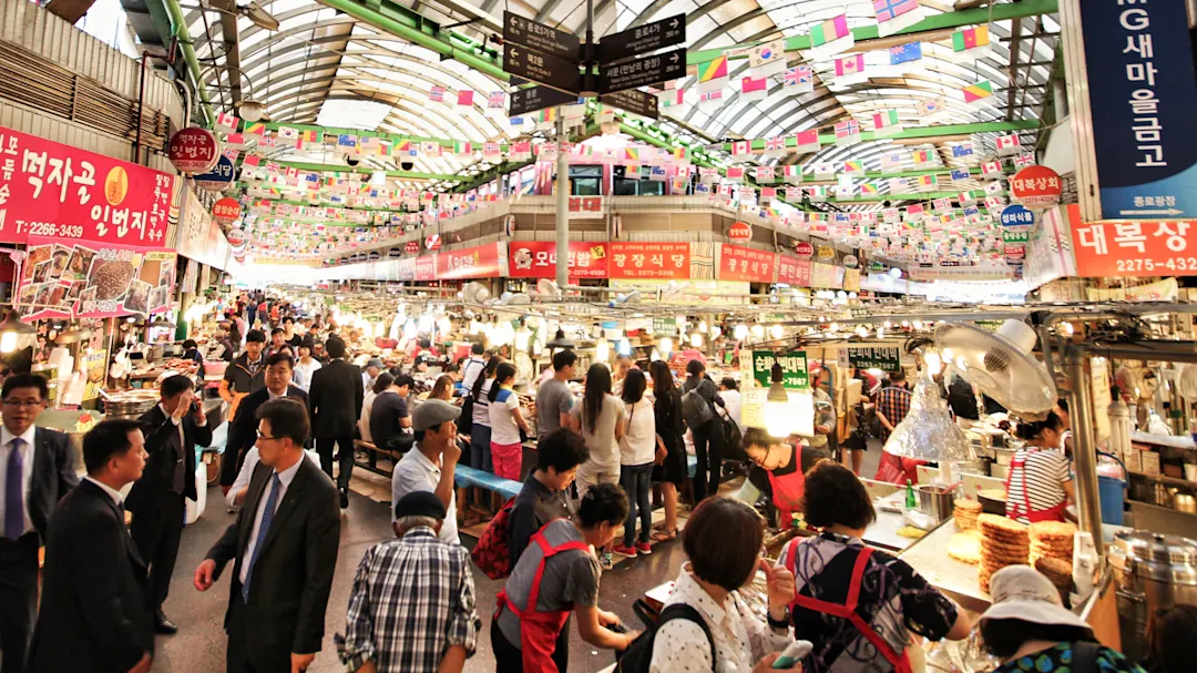 Südkorea, Seoul, Gwangjang Market Belebter traditioneller Gwangjang Markt mit Essensständen, geschäftigem Treiben und bunten Fahnen. Seoul, Südkorea.