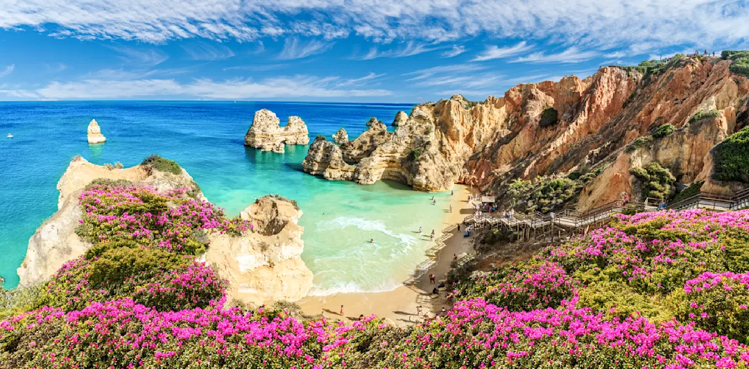 Felsige Bucht mit türkisfarbenem Wasser und Sandstrand, umgeben von Klippen, Algarve, Portugal.