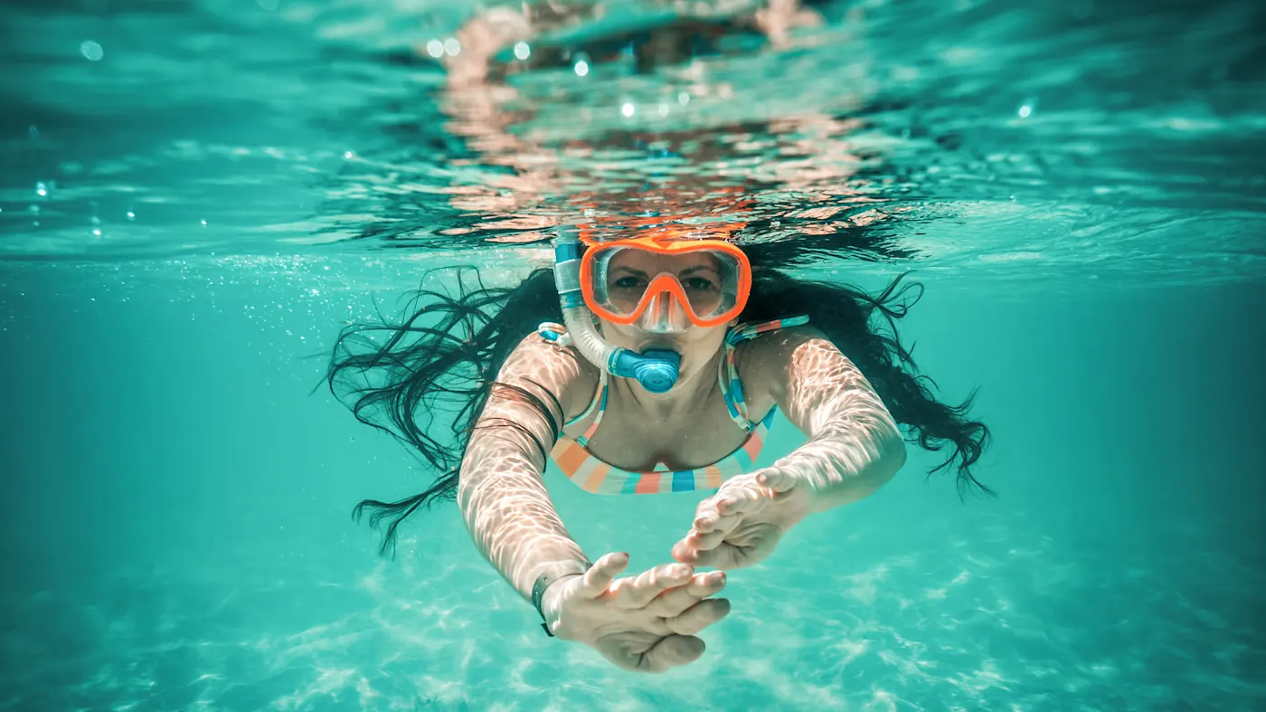 Une femme avec un tuba et un masque de plongée nage sous l'eau dans une mer turquoise et claire. Sri Lanka