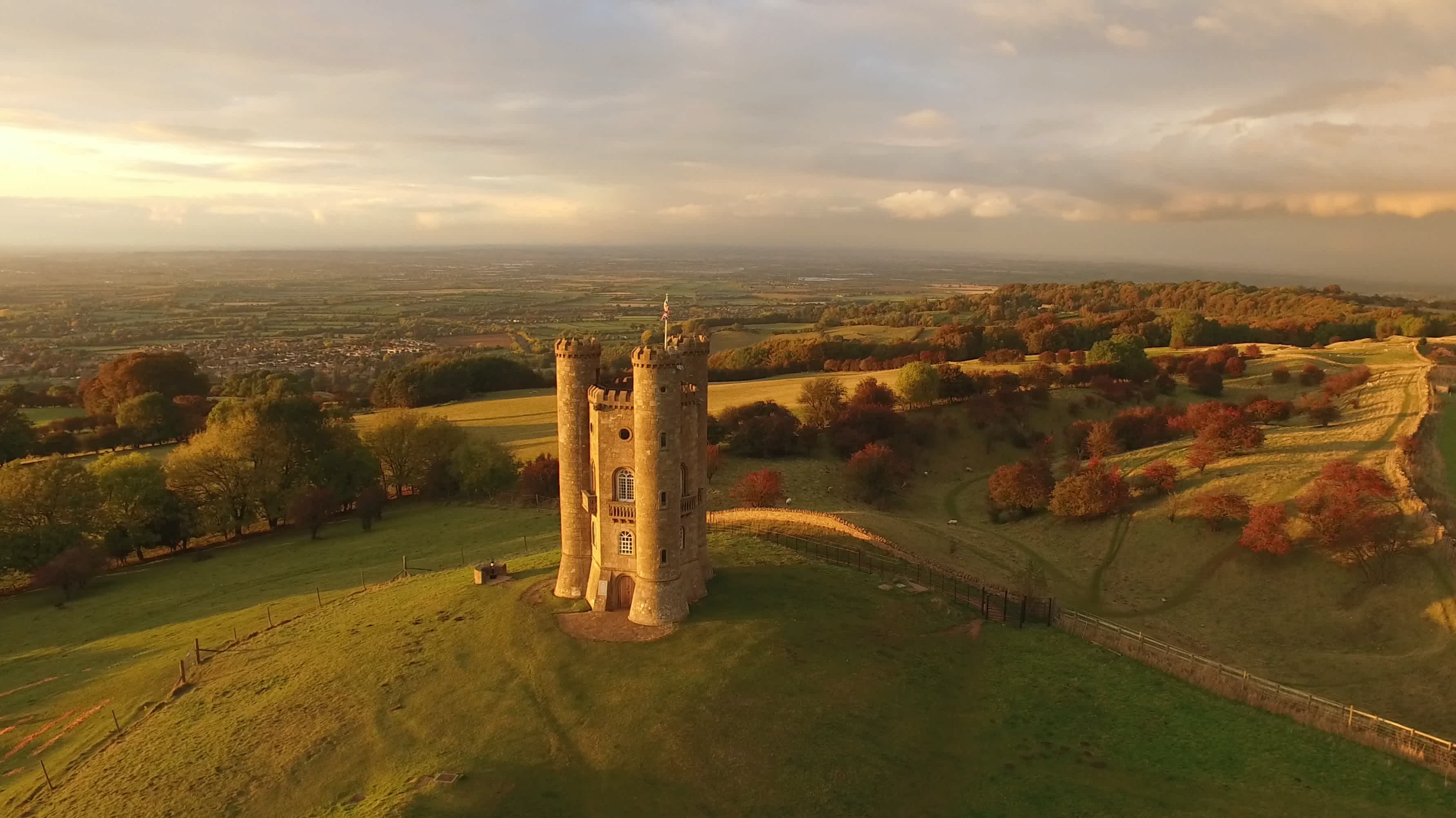 Broadway Tower in Cotswolds surrounded by woods glowing in autumn colors, England, Great Britain.