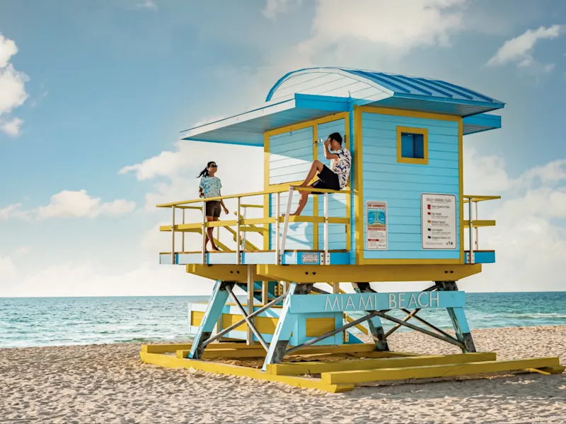 Bunte Rettungsschwimmerhütte am Strand mit Menschen und blauem Himmel. Miami, Florida, USA.