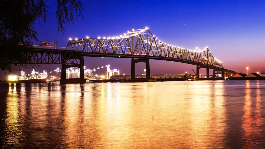 Die beleuchtete Mississippi River Bridge bei Nacht mit Reflexionen im Wasser. Baton Rouge, Louisiana, USA.