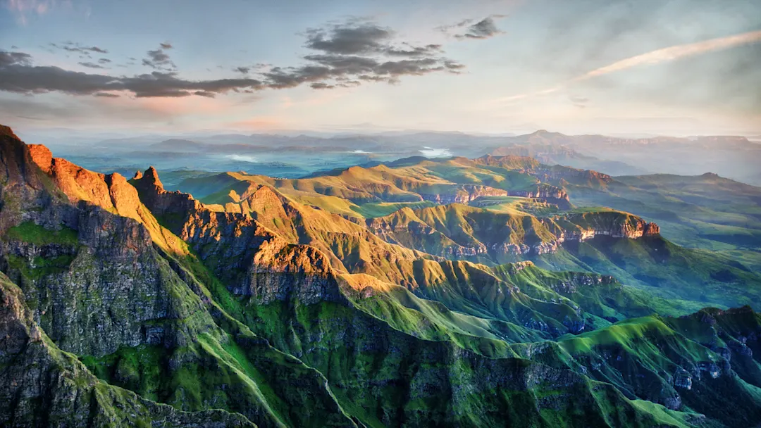 Drakensberge, Südafrika Atemberaubende Berglandschaft im Sonnenuntergang mit grünen Hügeln und felsigen Klippen, Drakensberge, Südafrika