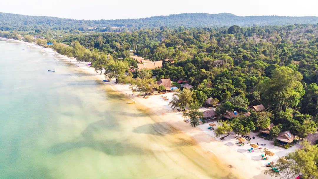 Luftaufnahme eines tropischen Strandes mit grüner Vegetation und Hütten. Koh Rong Samloem, Kambodscha.