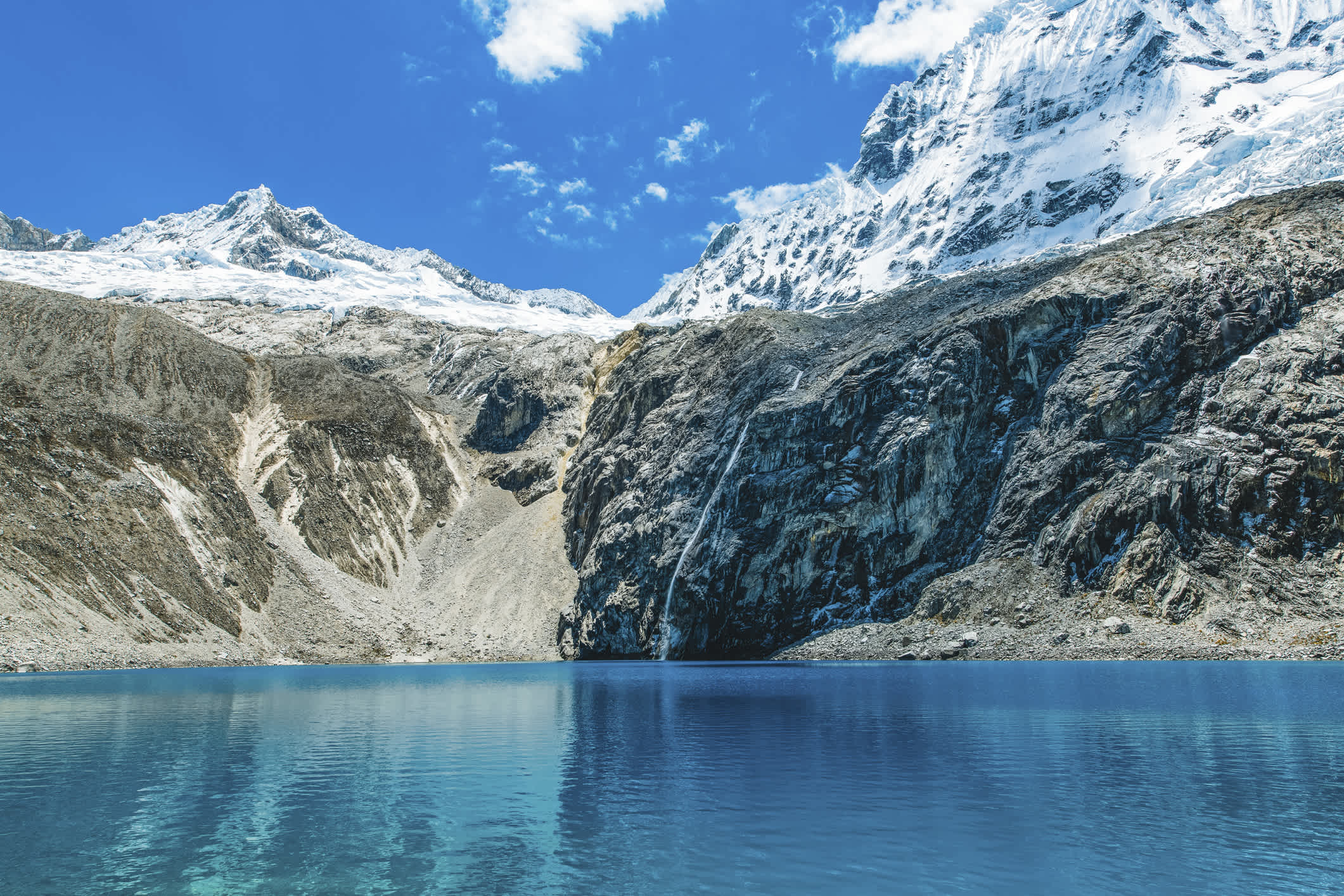 Kristallklarer Gletschersee mit Wasserfall hoch oben in den Anden