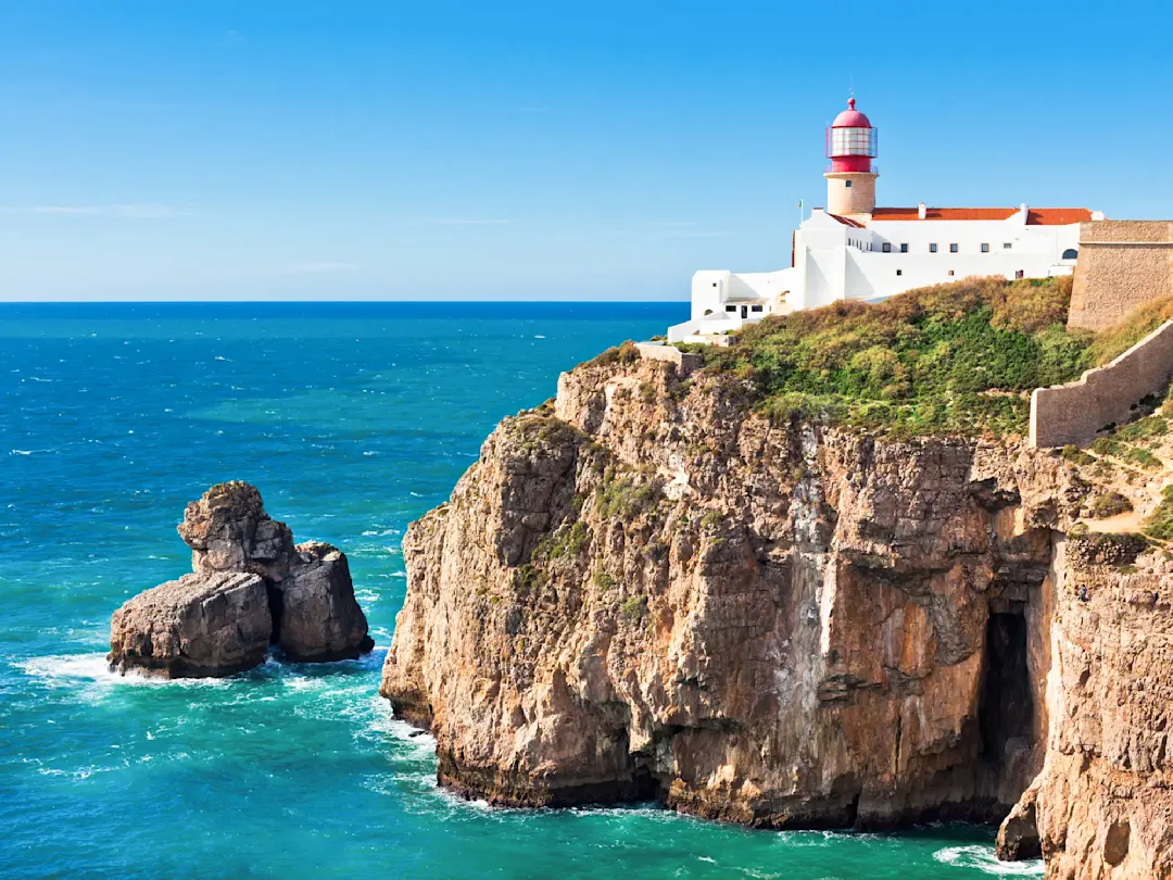 Weißer Leuchtturm auf einer Klippe mit Blick auf das Meer, Sagres, Algarve, Portugal.
