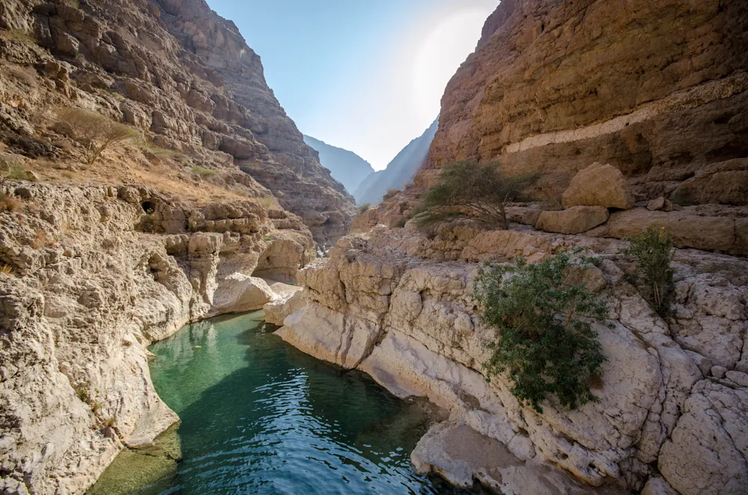 Eine felsige Schlucht mit klarem Wasser, das sich durch das Tal zieh, Wadi Shab, Oman.

