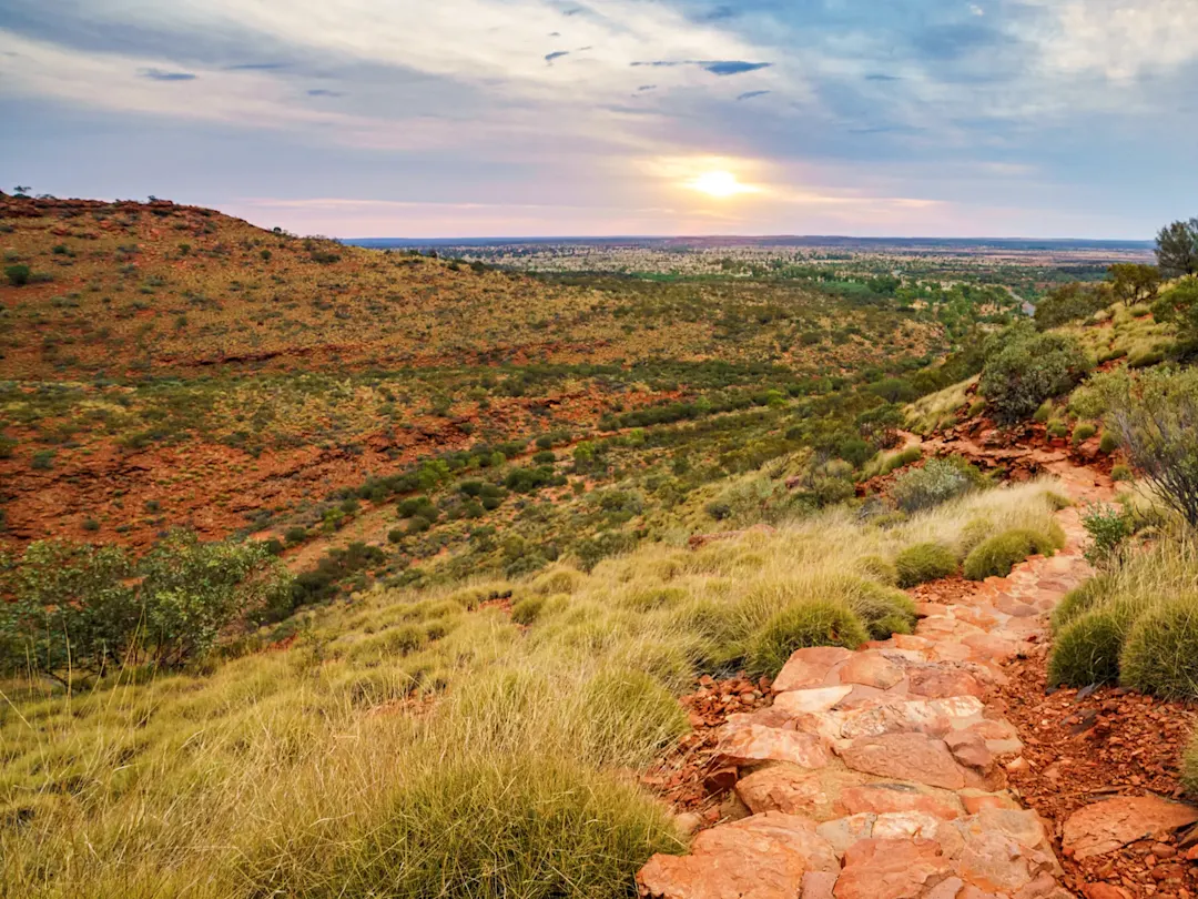 Wanderweg durch rote Hügel bei Sonnenuntergang. Kings Canyon, Northern Territory, Australien.
