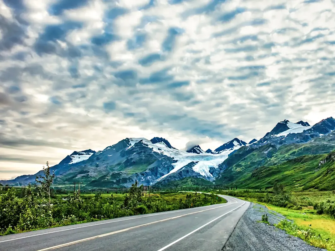 Straße führt durch grüne Berge mit Gletscherblick. Valdez, Alaska, USA.

