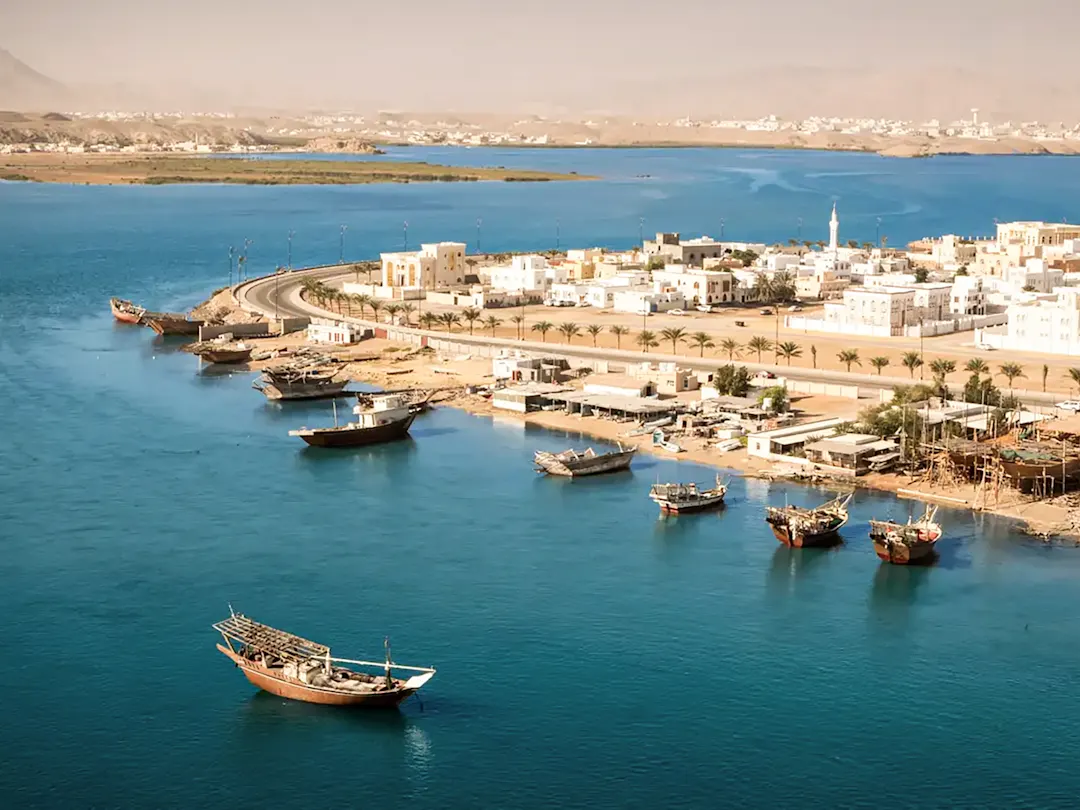 Küstenstadt Sur in Oman mit traditionellen Dhows, weißen Gebäuden und türkisfarbenem Wasser. Oman.